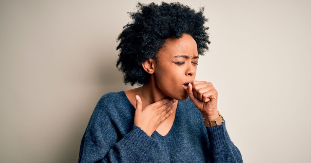 Young beautiful African American afro woman with curly hair wearing casual sweater feeling unwell and coughing as symptom for cold or bronchitis. Health care concept.