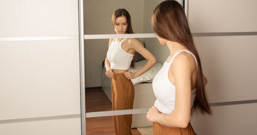 Teen anorexia, bulemia, skinny teen girl looks in the mirror and sees herself fat