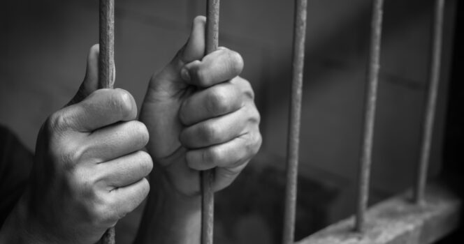 Man holds prison bars. Credit: Shutterstock