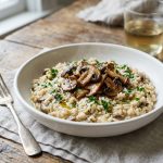 Overhead view of creamy mushroom risotto topped with sautéed mushrooms and a drizzle of truffle oil