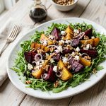 Overhead view of roasted beet and goat cheese salad with walnuts and arugula on a white platter